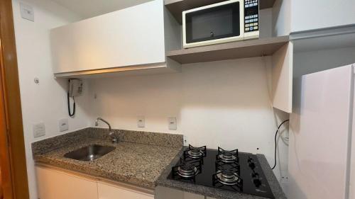 a kitchen with a stove and a microwave at Refúgio Beira Lago- Life Resort in Brasilia