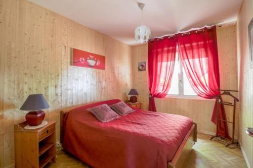 a bedroom with a red bed and a window at Gite des landes de la houssais in Guichen