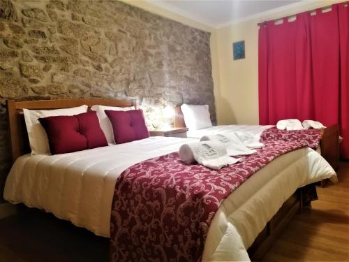 1 dormitorio con 1 cama grande y cortinas rojas en Casa de Maçaneira en Miranda do Douro