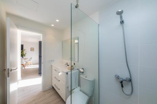 a bathroom with a toilet and a glass shower at White suites 3 in Cala d´Or
