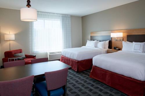 a hotel room with two beds and a table and chairs at TownePlace Suites by Marriott Cleveland Solon in Solon