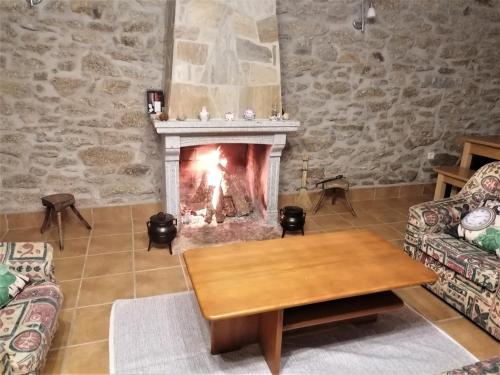 a living room with a fireplace and a table at Casa de Maçaneira in Miranda do Douro