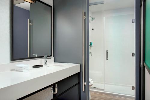 a bathroom with a sink and a mirror and a shower at Aloft Dallas DFW Airport Grapevine in Coppell