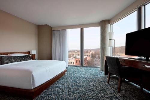 a hotel room with a bed and a desk and a television at Ithaca Marriott Downtown on the Commons in Ithaca