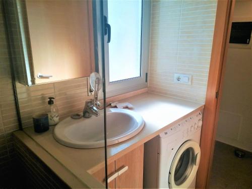 a bathroom with a sink and a washing machine at Global Immo 3360 LES MARINES GARBI 4-2 in Roses