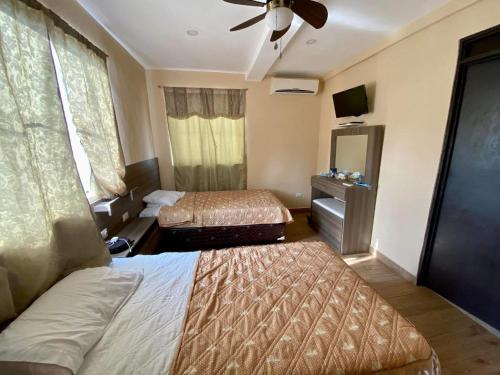 a hotel room with two beds and a ceiling fan at Habitaciones Casa Cuscatlan in Tamanique