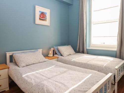 2 camas individuales en un dormitorio con ventana en Blue Skies, en Ilfracombe