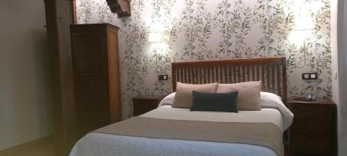 a bedroom with a bed with two pillows and wallpaper at La Casona de Revolgo in Santillana del Mar
