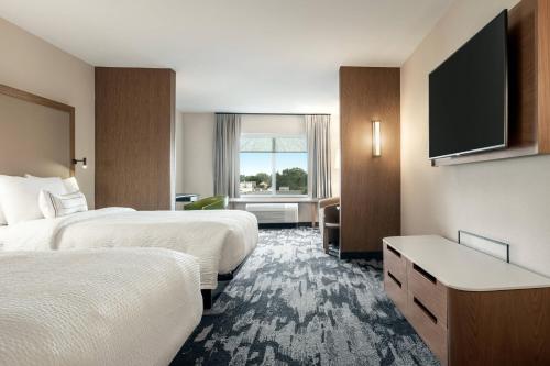 a hotel room with two beds and a flat screen tv at Fairfield Inn & Suites by Marriott Milwaukee West in West Milwaukee