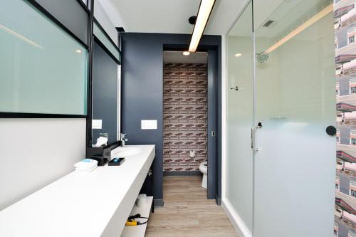 a bathroom with a sink and a glass shower at Aloft North Kansas City in Kansas City