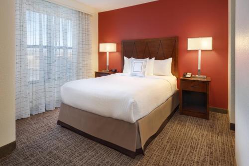 a bedroom with a large bed with red walls at Residence Inn Grand Junction in Grand Junction