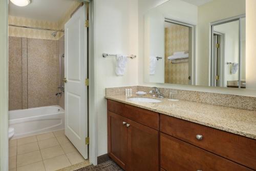 a bathroom with a sink and a tub and a mirror at Residence Inn Grand Junction in Grand Junction