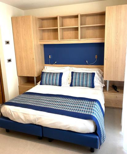 a bedroom with a bed with blue walls and shelves at Hotel Zurigo in Varazze