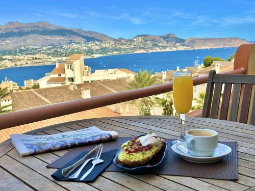 a table with a cup of coffee and a piece of cake and a drink at Albir Hills Apartments in Albir