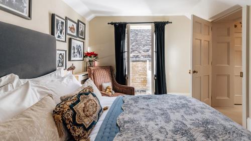 a bedroom with a bed and a chair and a window at Singer House in Chipping Campden