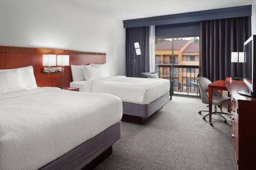 a hotel room with two beds and a balcony at Courtyard Charlotte Arrowood in Charlotte