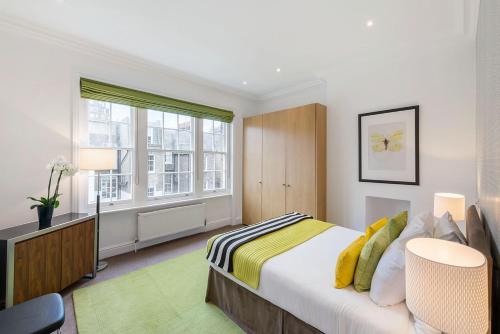Habitación blanca con cama y ventana en Chelsea - Draycott Place by Viridian Apartments, en Londres
