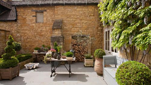 a patio with a table with plants in front of a building at Singer House in Chipping Campden