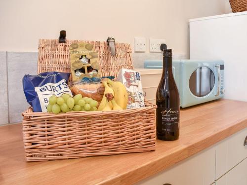 a basket of fruit and a bottle of wine on a counter at Carpenters Cottage in Upwey