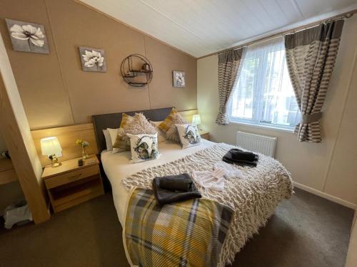 Rudd lake Luxury lakeside lodge with fishing & hot tub@Tattershall في تاتيرشال: غرفة نوم بسرير ونافذة