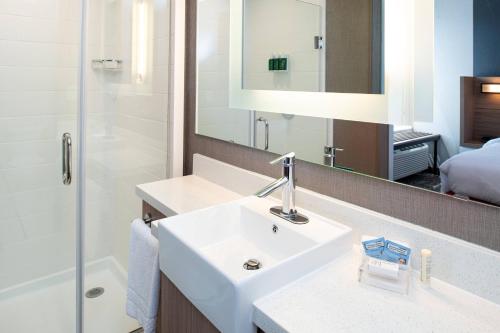 a bathroom with a sink and a shower and a mirror at SpringHill Suites by Marriott Kansas City Northeast in Kansas City