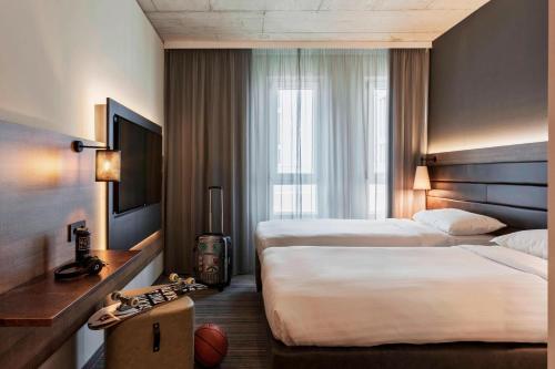 a hotel room with two beds and a window at MOXY Frankfurt East in Frankfurt