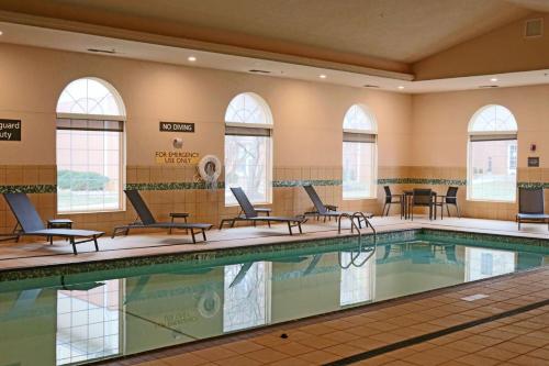 a pool in a hotel with chairs and tables at Residence Inn Kansas City Airport in Kansas City