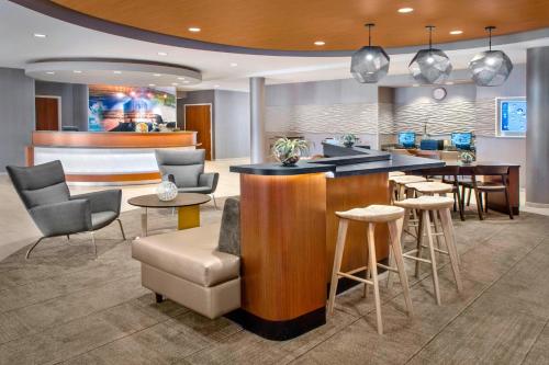 a lobby with a bar with chairs and tables at SpringHill Suites Long Island Brookhaven in Bellport
