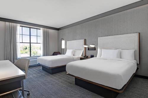 um quarto de hotel com duas camas e uma secretária em Courtyard by Marriott Manhattan Aggieville em Manhattan