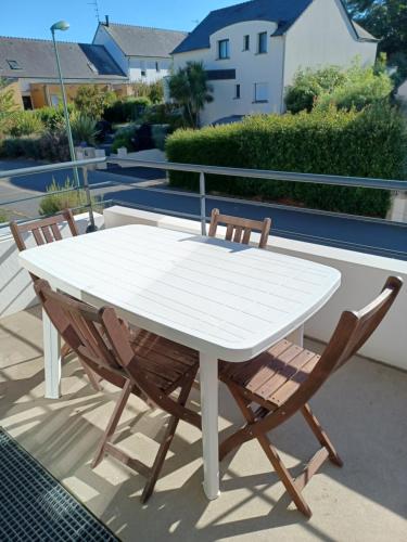 - une table blanche et 2 chaises sur la terrasse dans l'établissement Grand Appartement 2P dans immeuble PMR, à Guidel