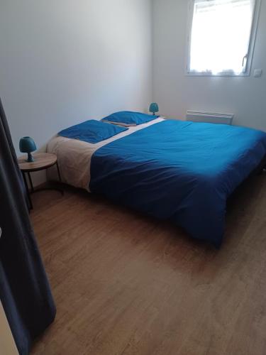 - un lit dans une chambre avec une couette bleue dans l'établissement Grand Appartement 2P dans immeuble PMR, à Guidel