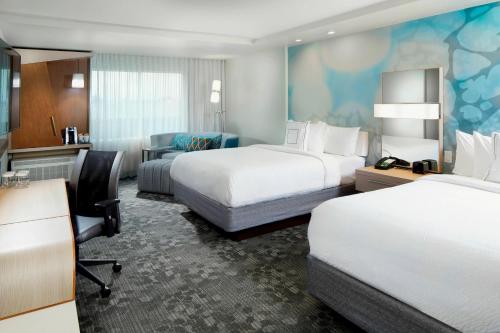 a hotel room with two beds and a desk at Courtyard by Marriott Houston Intercontinental Airport in Houston