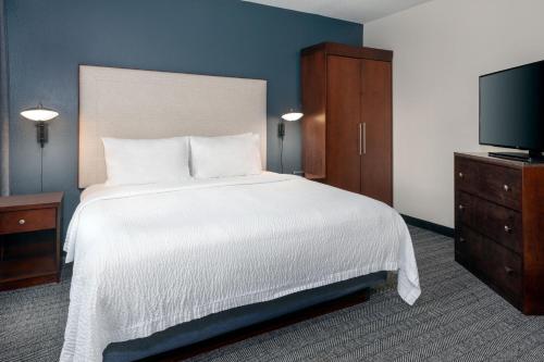 a bedroom with a white bed and a flat screen tv at Courtyard by Marriott Sarasota at University Town Center in Sarasota