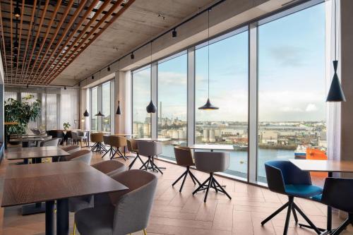 a restaurant with tables and chairs and large windows at Residence Inn by Marriott Amsterdam Houthavens in Amsterdam