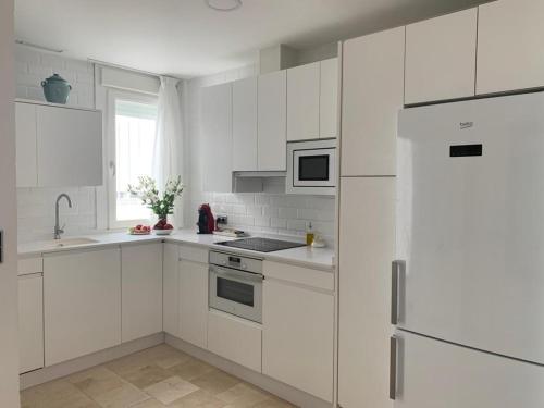 een witte keuken met witte kasten en een koelkast bij Coral Oro en la Caleta Ha Apartment in Cádiz