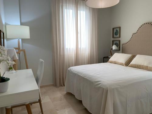 een witte slaapkamer met een bed, een tafel en een bureau bij Coral Oro en la Caleta Ha Apartment in Cádiz
