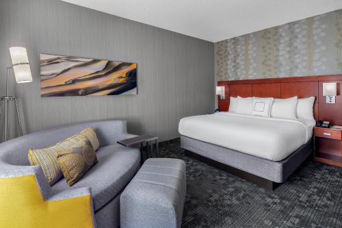 a hotel room with a bed and a couch at Courtyard by Marriott Pittsburgh Airport in Coraopolis