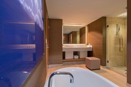 a bathroom with a tub and a sink and a mirror at The Westin at The Woodlands in The Woodlands