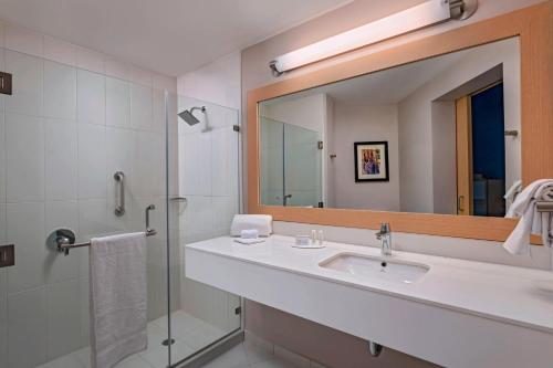 a bathroom with a sink and a mirror and a shower at Fairfield by Marriott San Salvador in San Salvador