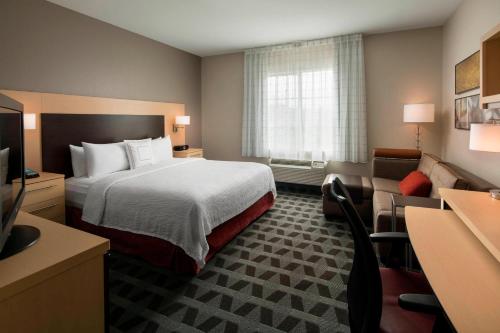 TownePlace Suites by Marriott San Diego Carlsbad / Vista في فيستا: غرفه فندقيه بسرير واريكه