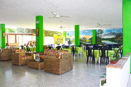 un restaurant avec des colonnes vertes, des tables et des chaises dans l'établissement Casa de Campo Peñalisa Hotel campestre, à Ricaurte
