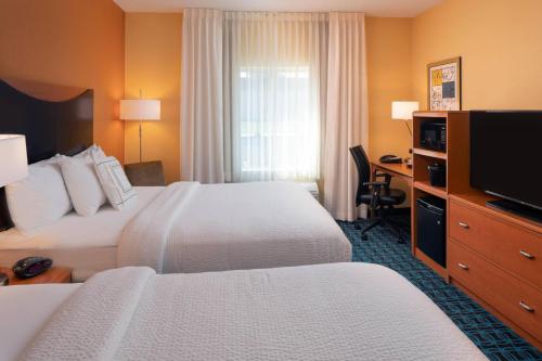 a hotel room with two beds and a flat screen tv at Fairfield Inn & Suites Lafayette I-10 in Lafayette