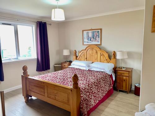 a bedroom with a wooden bed with a red bedspread at The Wee Gem - 9 Milking Hill Park in Stornoway