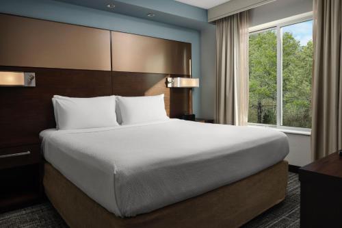Cama grande en habitación de hotel con ventana en Residence Inn by Marriott Grand Rapids Airport, en Grand Rapids