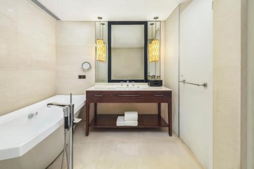 a bathroom with a sink and a tub and a mirror at Sheraton Shanghai Jiading Hotel in Jiading