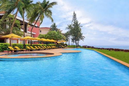 una piscina in un resort con sedie e ombrelloni di Goa Marriott Resort & Spa a Panaji