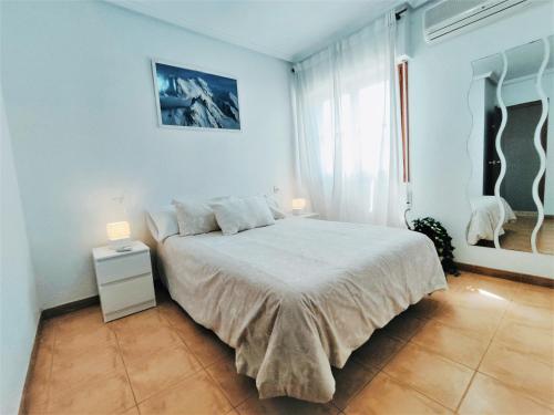 a white bedroom with a bed and a window at Bonita casa al lado de la playa en Santa Pola in Santa Pola