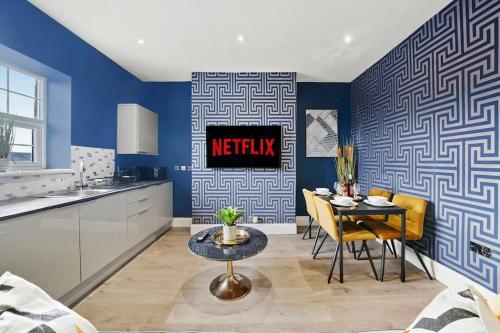 a kitchen and dining room with blue walls and a table at Platinum Grove Modern Flat in Kent