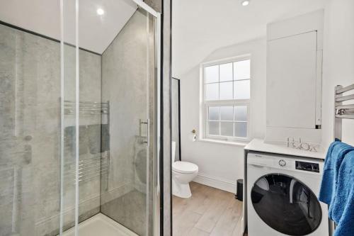 y baño con ducha y lavadora. en Platinum Grove Modern Flat, en Kent