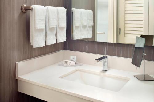 a bathroom with a white sink and a mirror at Courtyard by Marriott Raleigh Cary in Cary